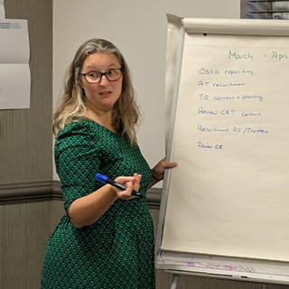 Megan McHaney is facilitating a team coaching session in front of a flipchart